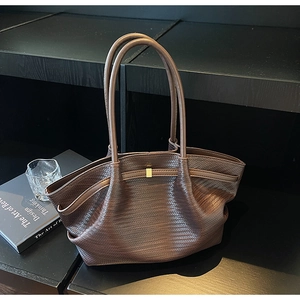 Detailed view of dark brown woven leather tote with refined texture and gold buckle