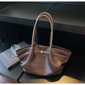 Close-up of dark brown woven tote bag with fine leather texture and gold buckle