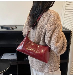 Détail du sac à bandoulière en cuir verni rouge foncé avec coutures décoratives