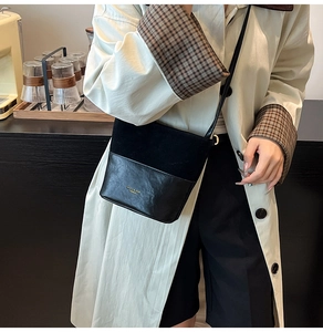 Detail of a chic black bucket bag featuring textured suede and smooth leather patchwork