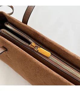 Detail of premium golden metal zipper and brown faux suede texture on vintage baguette bag