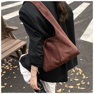 Sac hobo marron en cuir dépoli avec cordon et breloque cœur porté par le mannequin