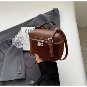 Detail of brown contrast leather crossbody bag featuring matte finish and silver hardware