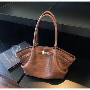 Detail of brown faux-woven tote bag texture with elegant handle on dark display