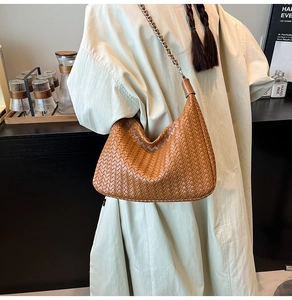 Detail of a brown woven leather hobo bag with silver metal chain and leather strap