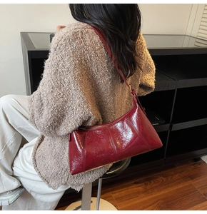 Gros plan d'un sac bordeaux brillant à texture froissée avec détails de zip doré chic