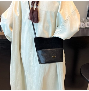 Detail of black bucket bag showing suede and faux leather textures on white dress
