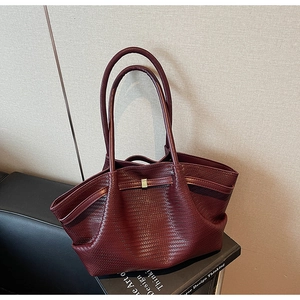 Detailed close-up of burgundy woven leather tote bag with classic metal clasp closure