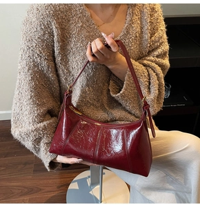Détail d'un sac sous les bras en cuir verni bordeaux brillant avec texture plissée