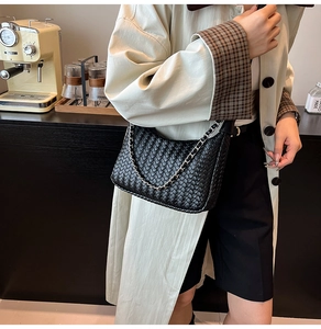 Macro shot of black woven leather texture and elegant silver chain on women shoulder bag