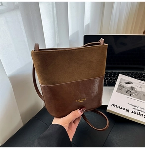 Detail of two-tone bucket bag showing brown matte and leather contrast and logo