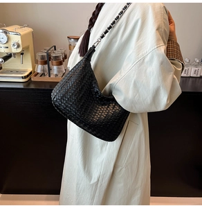 Detail of black woven hobo bag with leather texture and silver chain strap for women