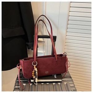 Detail of burgundy faux suede tote bag with long straps and ethnic beaded charm ornament