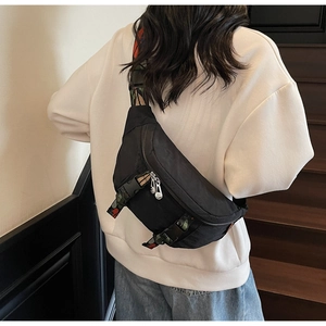 Detailed view of black nylon chest bag with colorful striped strap on a female model