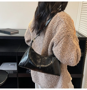 Détail du sac sous le bras noir plissé brillant avec forme de croissant et boucle en métal