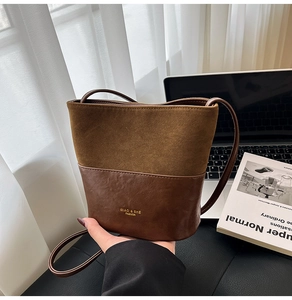 Detailed shot of bicolor bucket bag with suede and leather textures and gold logo