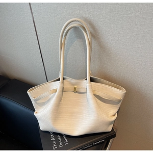 Detailed view of beige woven tote bag with gold buckle on design thinking book