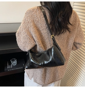 Détail du sac porté épaule en cuir verni noir avec surpiqûres losanges et boucle dorée