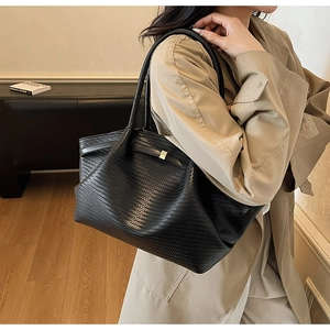 Detail of black woven leather tote bag with gold buckle and long shoulder strap