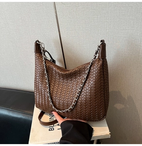 Detail of woven brown hobo bag showing texture, silver chain and long leather strap