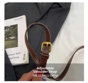 Close-up of adjustable brown leather shoulder strap with polished gold metal buckle