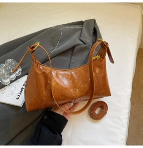Détail du sac à bandoulière en cuir verni caramel avec zip doré et bandoulière de rechange