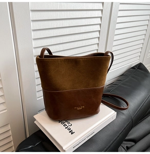 Close-up of brown bucket bag with dual-texture suede and smooth leather stitching