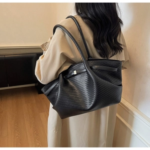 Detailed view of black woven faux leather tote bag showing fine texture and slim dual straps