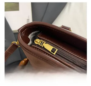 Detail of dark brown leather bucket bag with gold hardware and colorful beaded strap