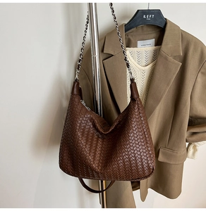 Detail of woven leather texture on a dark brown hobo bag with silver chain strap