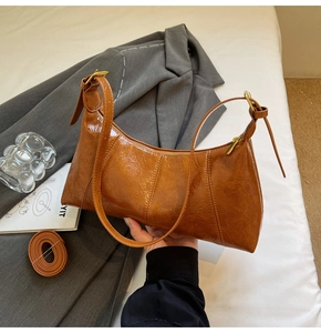Close-up of vintage brown oil-wax leather baguette bag with dual adjustable straps