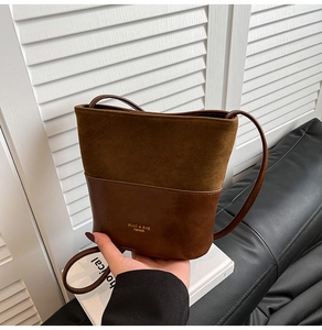 Close-up of retro brown bucket bag featuring contrast suede and smooth leather textures