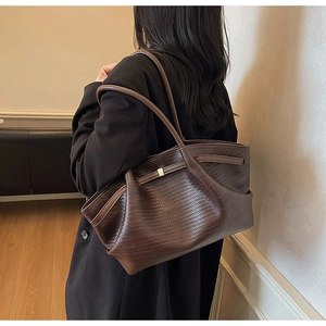 Detail of dark brown woven leather tote bag showing texture and slim shoulder straps