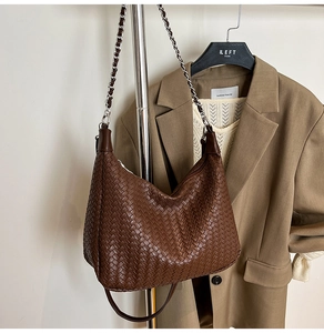 Detail of brown woven hobo bag with silver chain strap and leather texture on a display