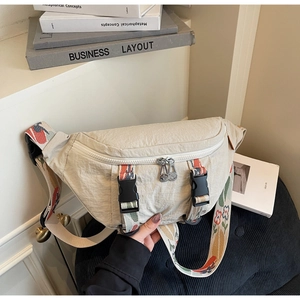 Detail of beige canvas chest bag featuring colorful floral jacquard wide shoulder strap