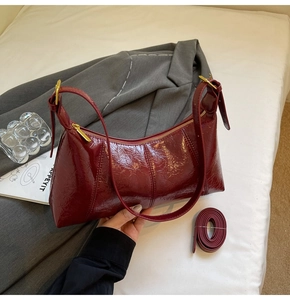 Détail du sac à main bordeaux en cuir verni plissé avec accessoires dorés et bandoulière