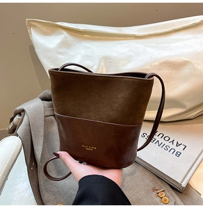 Detail of a brown two-tone crossbody bucket bag with textured contrast and gold logo