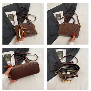 Detail view of leopard print crossbody bag with wooden bead charm and spacious interior