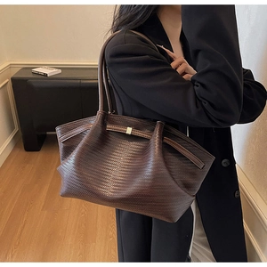 Detailed view of woven texture and metal buckle on dark brown leather tote bag