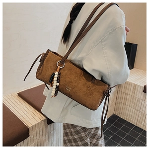 Detail of vintage brown suede shoulder bag with wooden bead tassel and side drawstring
