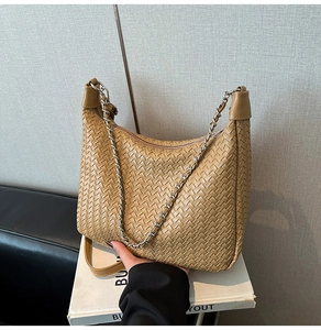 Close-up of khaki woven leather shoulder bag with silver chain and zipper detail