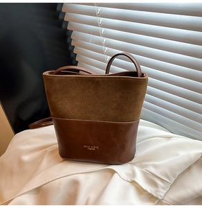 Detail of retro brown bucket bag featuring contrast textures and gold brand logo