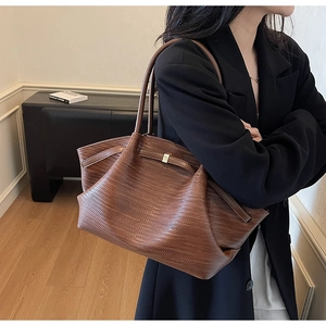 Close-up of deep brown woven texture tote bag featuring golden hardware and leather straps