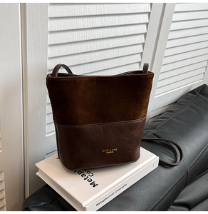 Detail of dark brown bucket bag with contrast textures on a white book backdrop