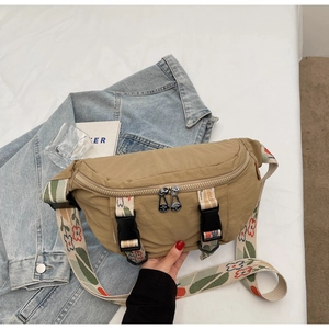 Detail view of khaki nylon chest bag with colorful floral embroidery and buckle straps