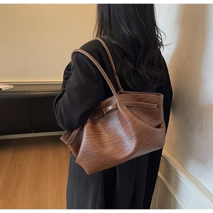 Detail of a dark brown woven tote bag showing leather texture and spacious over-the-shoulder fit