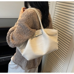 Chic cream tote bag with woven texture shown on shoulder for everyday style