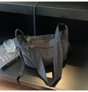 Dettaglio borsa a mezzaluna nera in nylon con tasche a zip e ampia tracolla regolabile