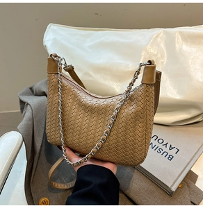 Close-up of khaki woven texture crescent bag with silver chain and leather strap