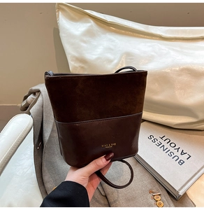 Close-up of retro bucket bag in dual-texture brown leather and suede with gold logo